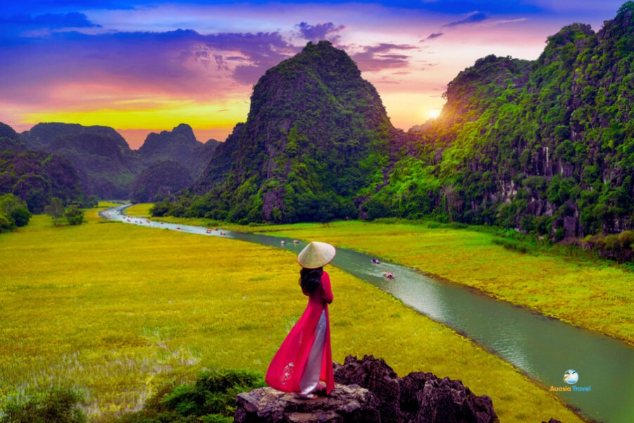 Vietnamese woman in red Ao Dai at Tam Coc sunset Ninh Binh – Auasia Travel